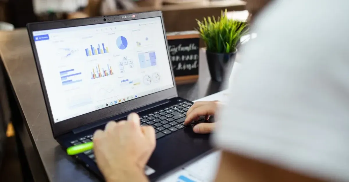 Professional reviewing automotive SEO results on laptop screen with data analytics charts and graphs displayed.
