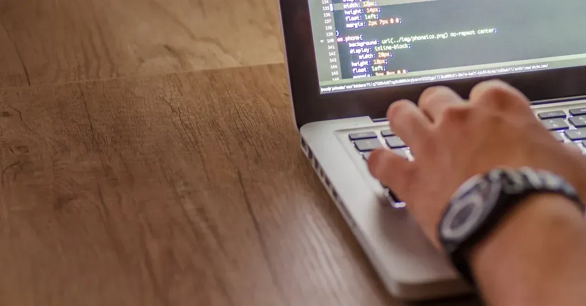 Developer typing technical SEO automotive code on laptop with HTML markup visible on screen.