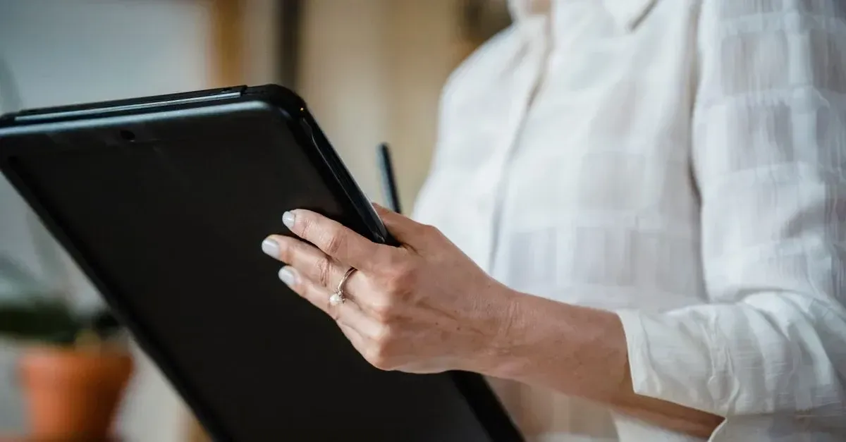 Person in white shirt holding tablet with stylus, reviewing website marketing mistakes on screen.