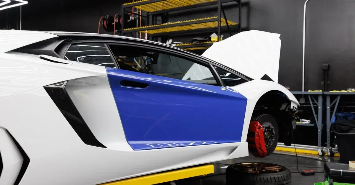 White and blue sports car with open door in professional detailing agency garage workshop.