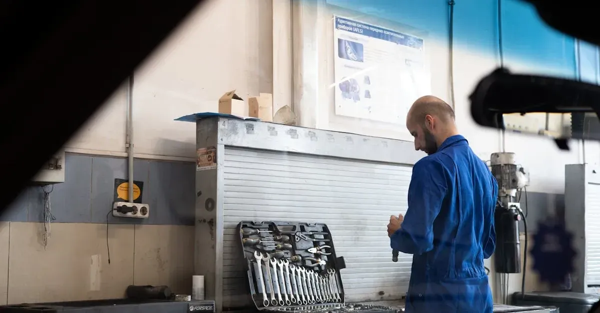 Mechanic reviewing service details on tablet in auto detailing shop workspace with tools and equipment visible.