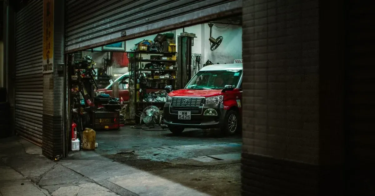 Red car in tint shop garage with equipment and tools, showing professional tint shop leads workspace setup.
