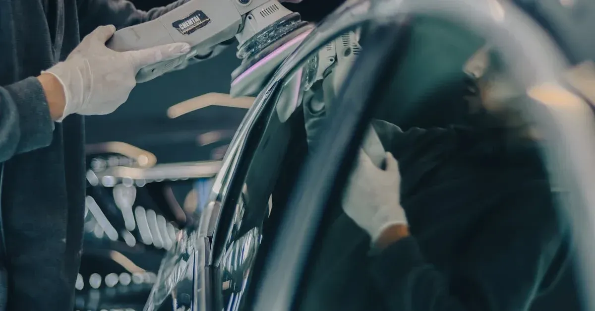 Technician holding digital tablet inspecting car surface for auto detailing leads and service quality.