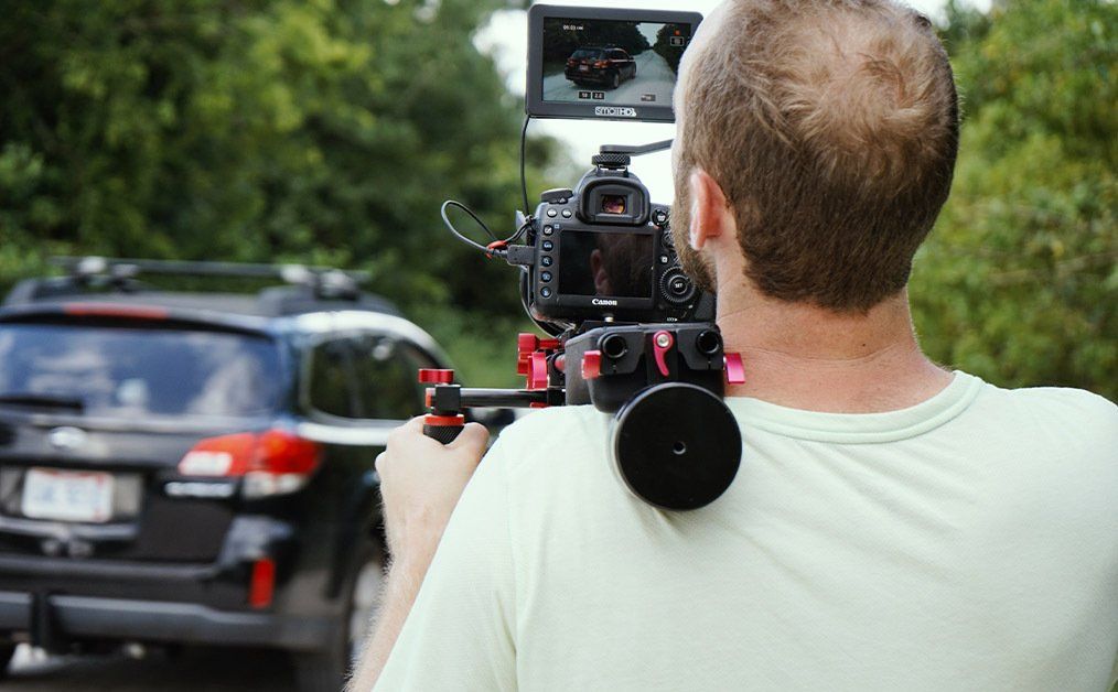 A man is taking a picture of a car with a camera.