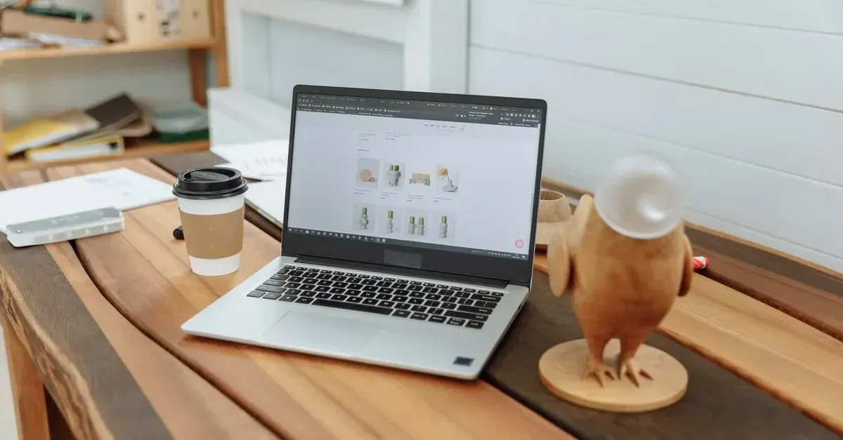 Laptop displaying auto tinting marketing design on wooden desk with coffee cup and glass in modern workspace.
