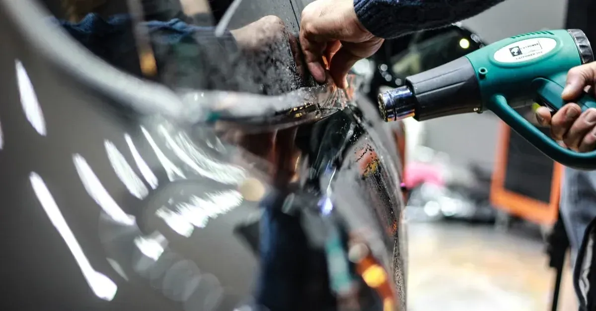 Professional using pressure washer to detail car exterior for car detailing website service showcase.