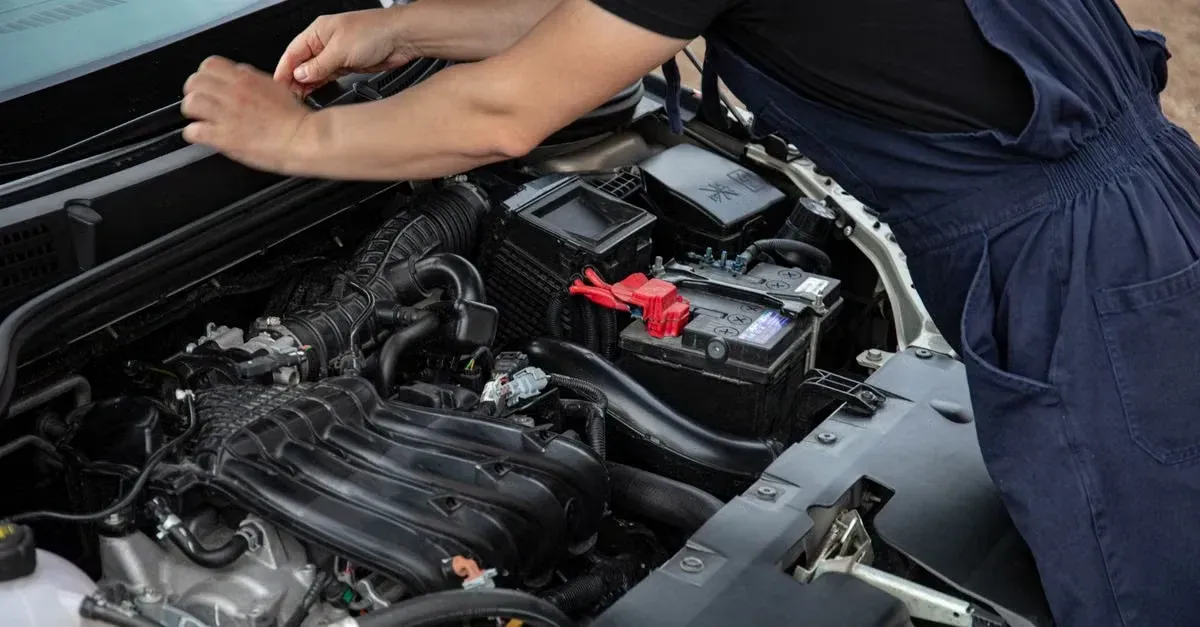 Mechanic checking car battery under open hood for SEO for automotive businesses maintenance.