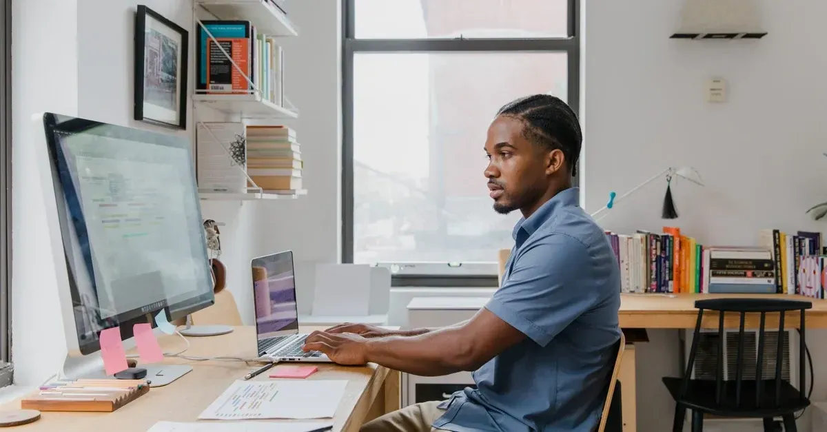 Man using CRM auto detailing software on desktop computer at bright modern workspace desk.