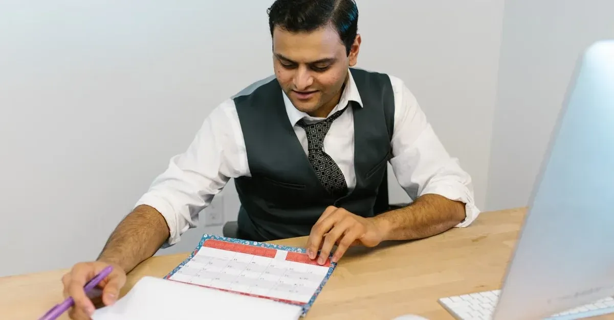 Professional man in vest reviewing project timeline and checklist at desk with laptop.