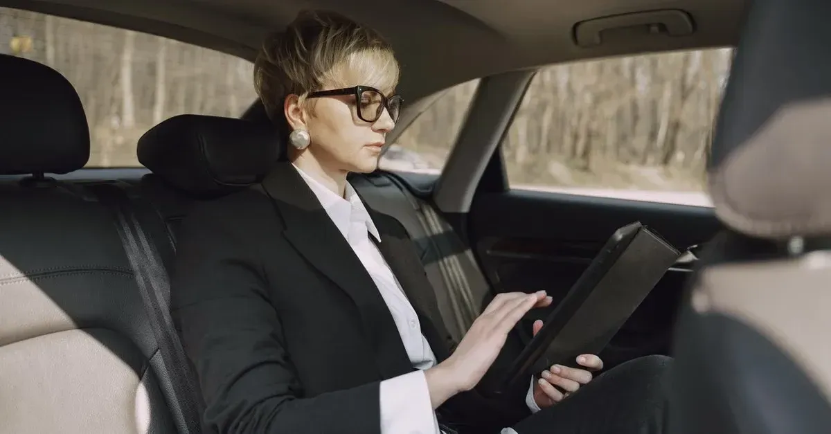 Professional in car holding tablet, demonstrating modern automotive advertising ideas for business growth.