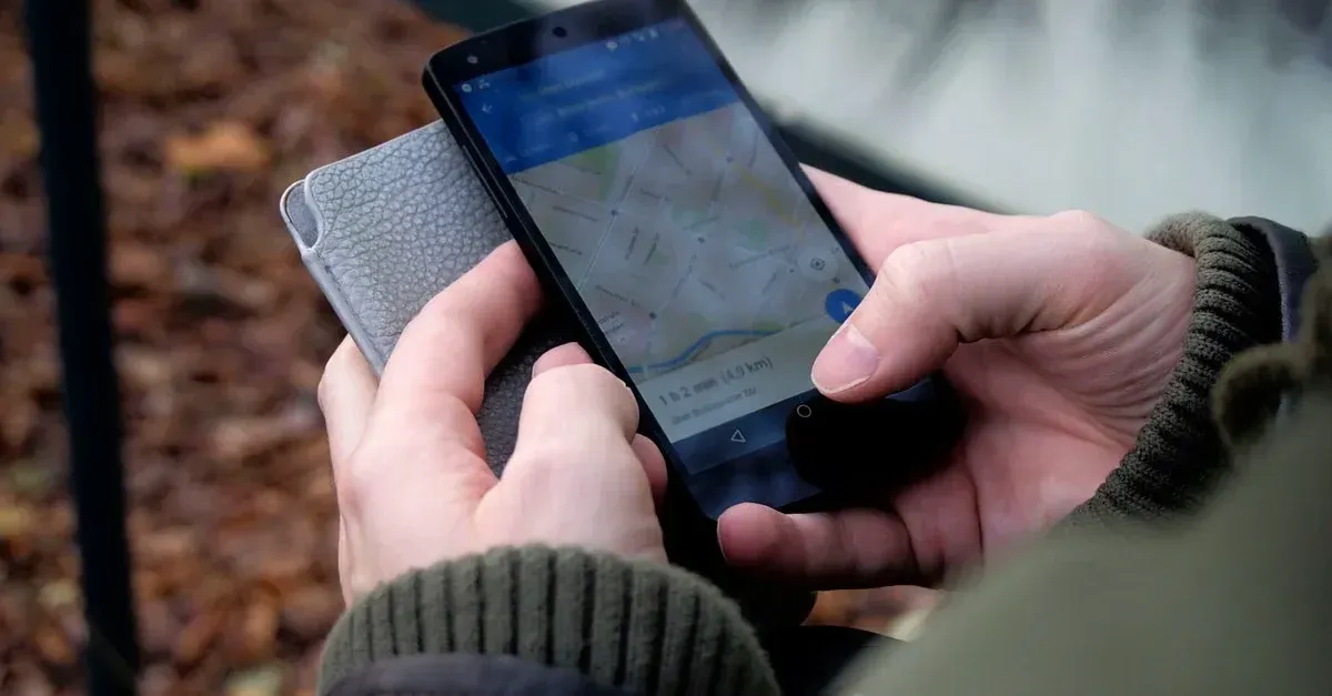 Hands holding smartphone displaying map search for local tint shop leads outdoors.