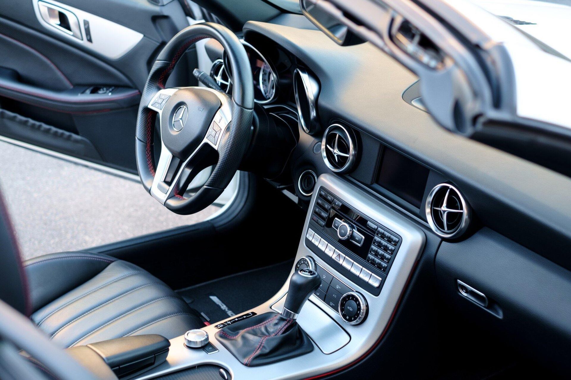 Interior of a silver Mercedes-Benz convertible with black leather seats and dashboard.