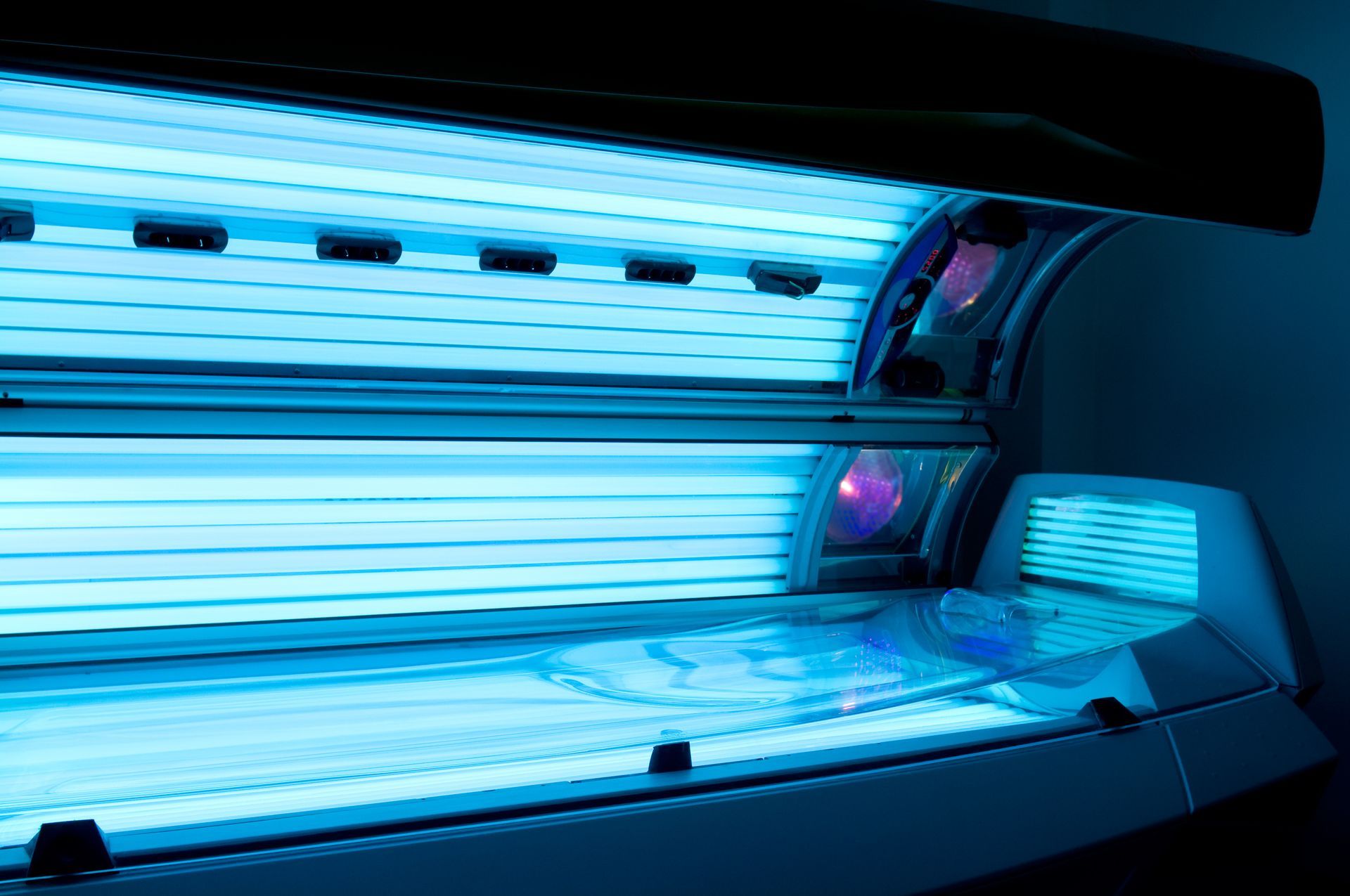 Blue tanning bed with illuminated tubes and reflective interior