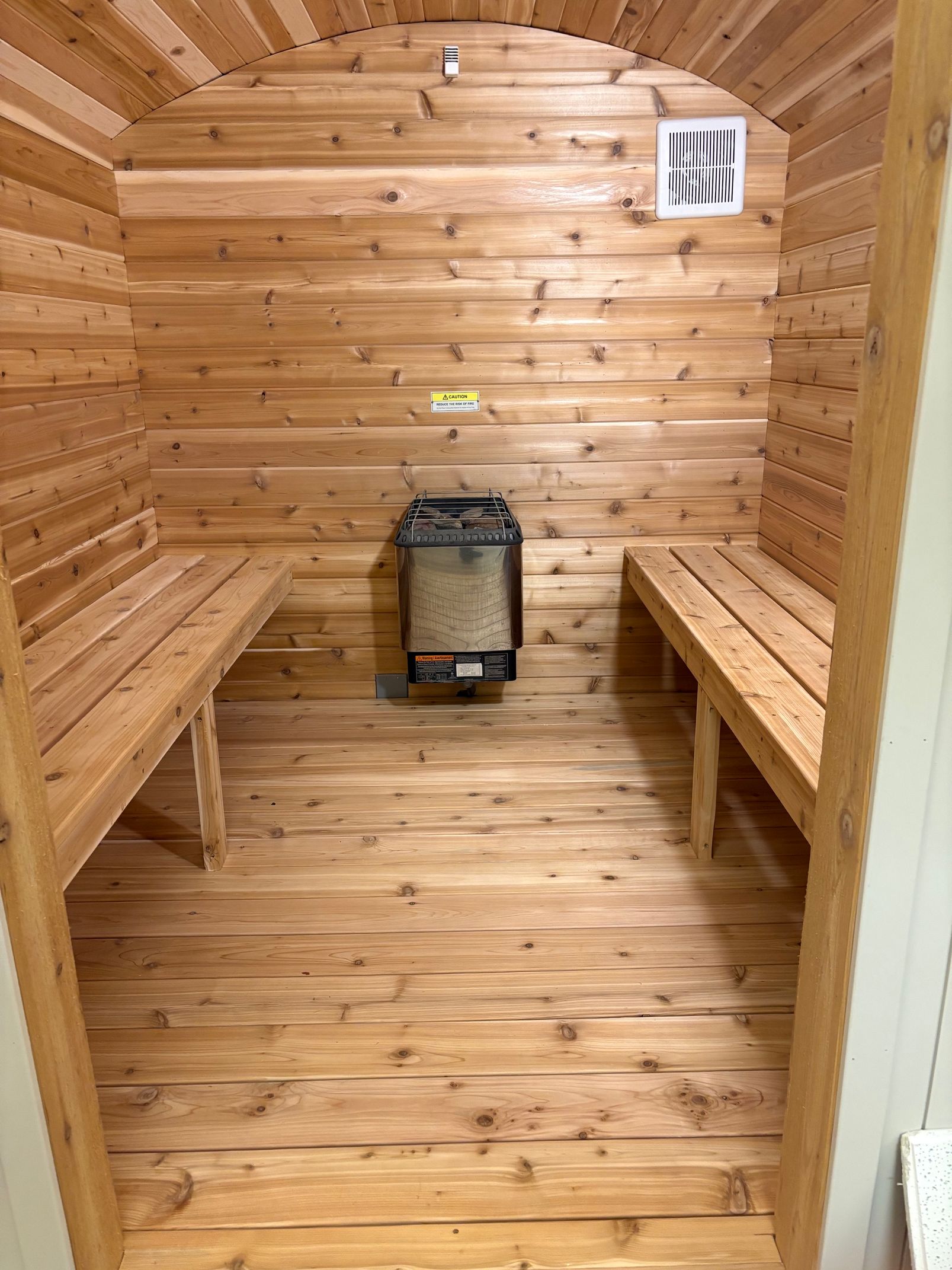 Red-lit sauna interior with wooden benches and slatted walls
