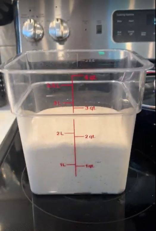 A measuring cup filled with white liquid is on a stove top.