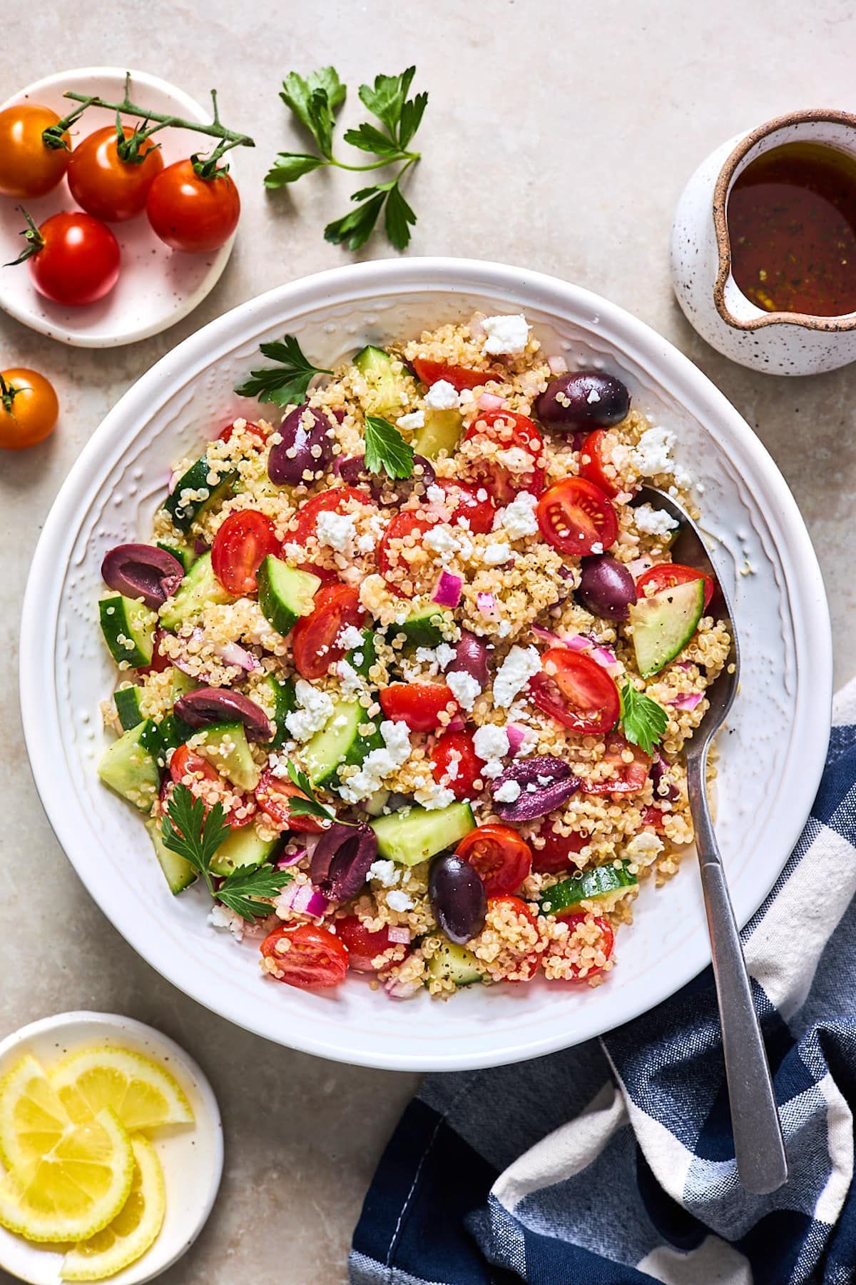 A white bowl filled with a salad with tomatoes , cucumbers , olives and feta cheese.