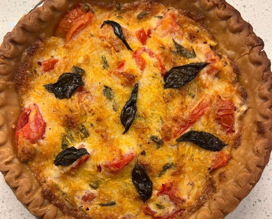 A close up of a pizza with tomatoes and basil on a table.