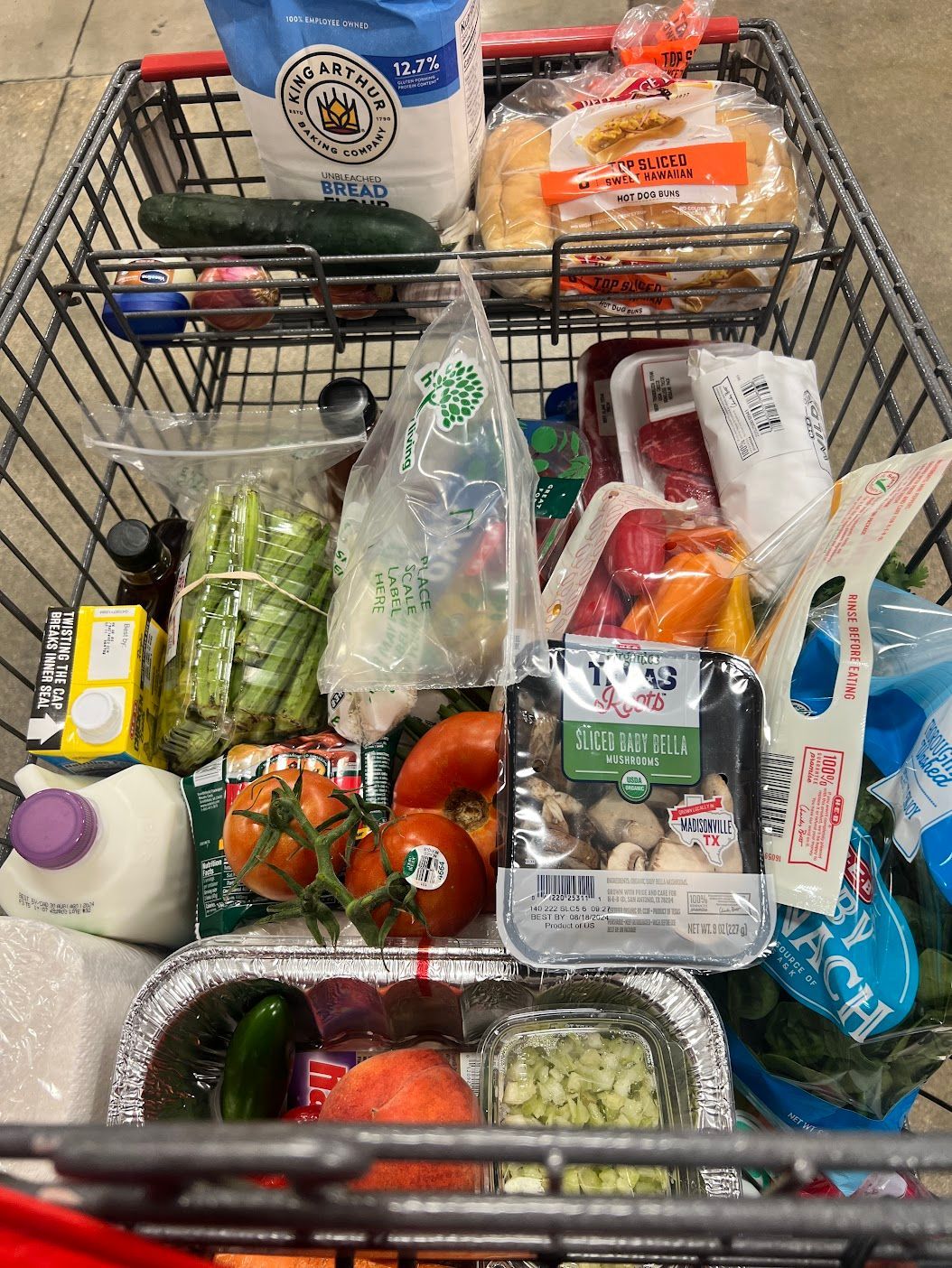 A shopping cart filled with a variety of groceries.