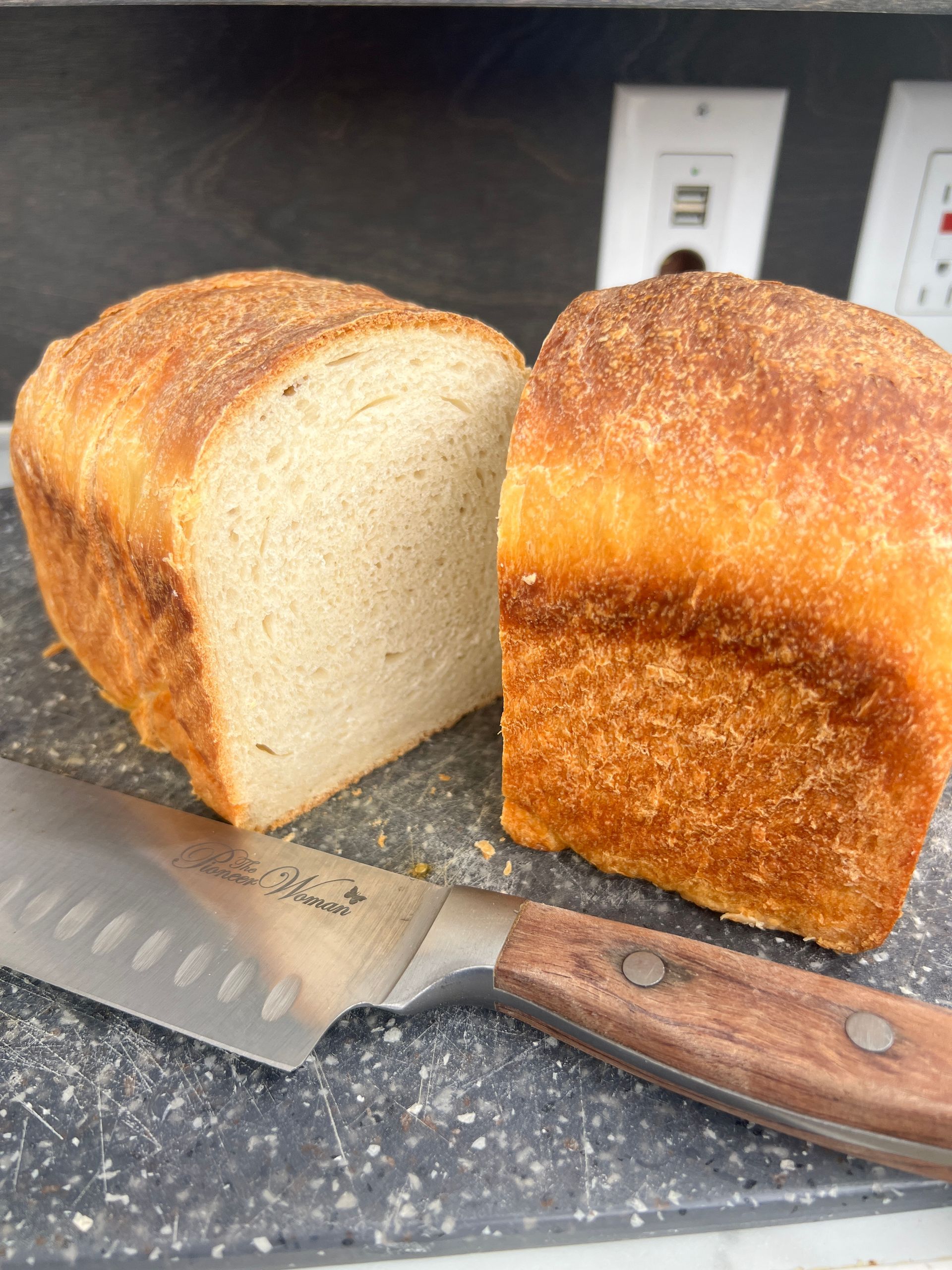 a loaf of bread is cut in half sitting on a cutting board