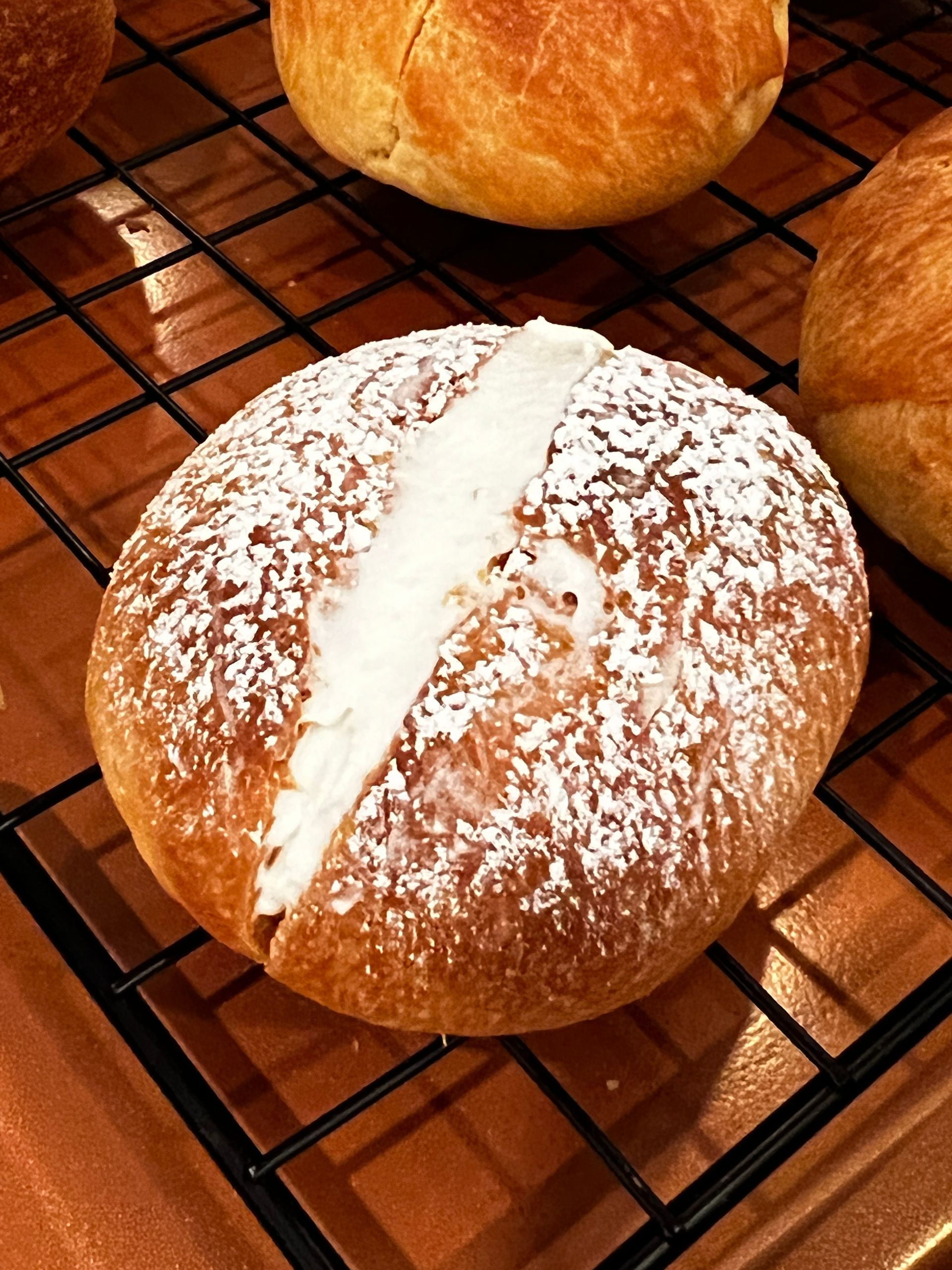 An Italian sweetbread with powdered sugar on it is sitting on a cooling rack.