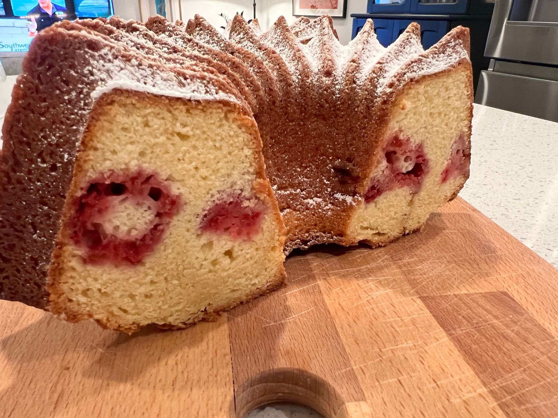 A bundt cake with a slice taken out of it is sitting on a wooden cutting board.