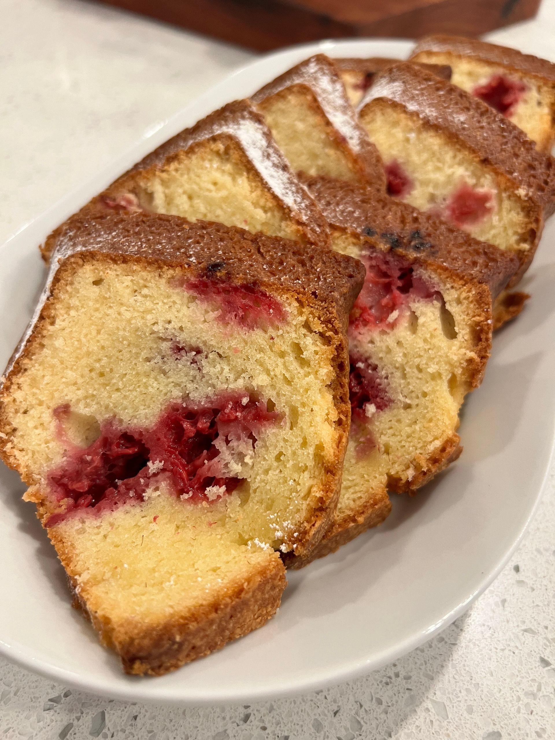 A white plate topped with slices of raspberry loaf cake.