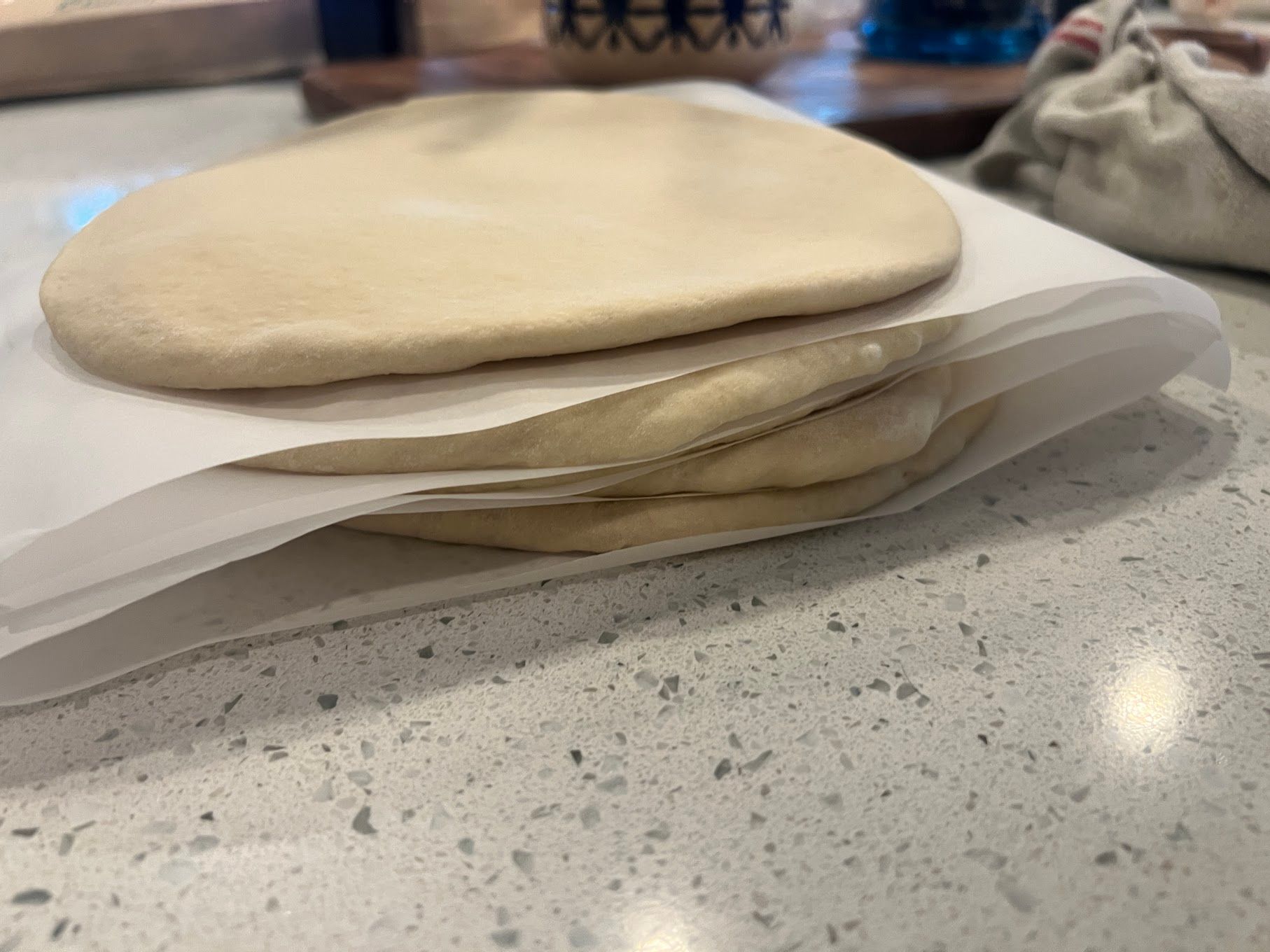 A stack of dough sitting on top of a piece of wax paper on a counter.