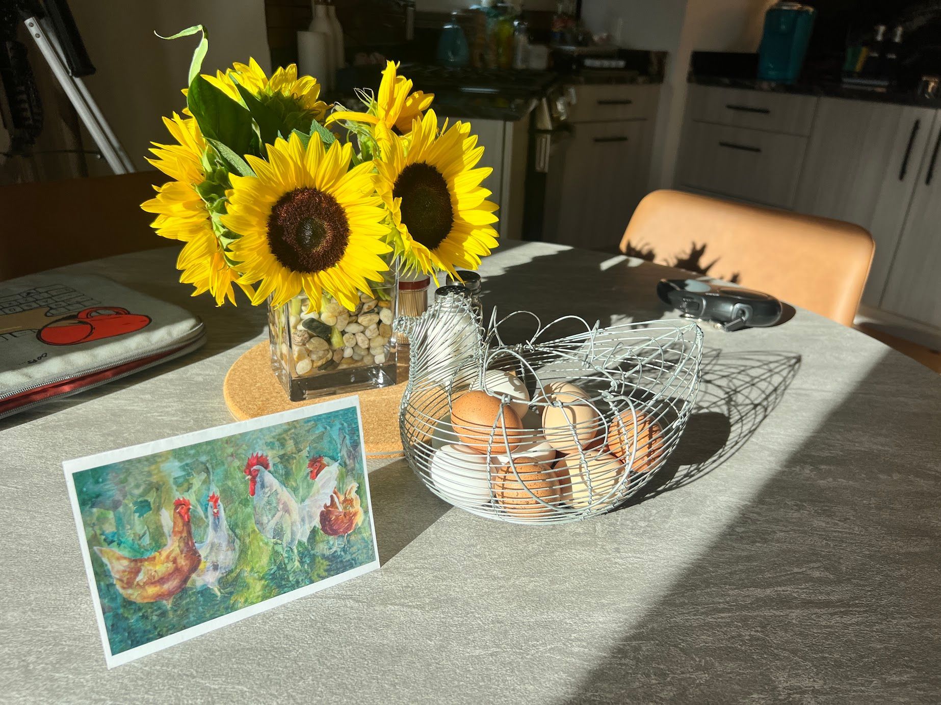 A table with a vase of sunflowers and a basket of eggs