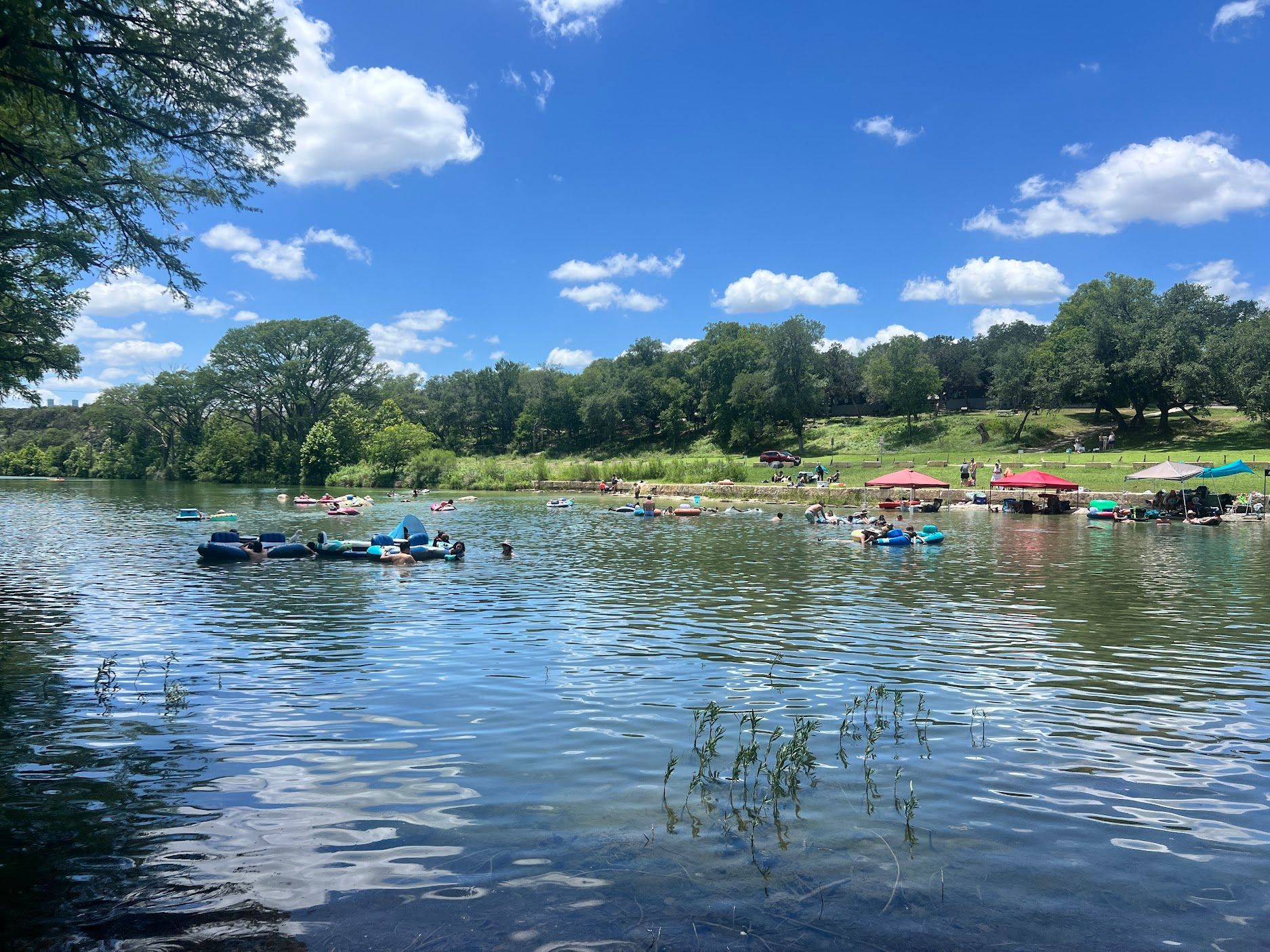 A lake filled with rafts and people on a sunny day.