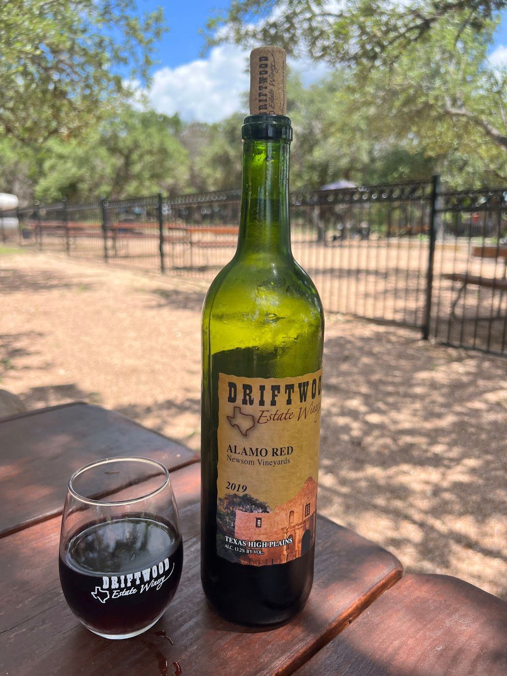 A bottle of driftwood wine is sitting on a wooden table next to a glass of wine.