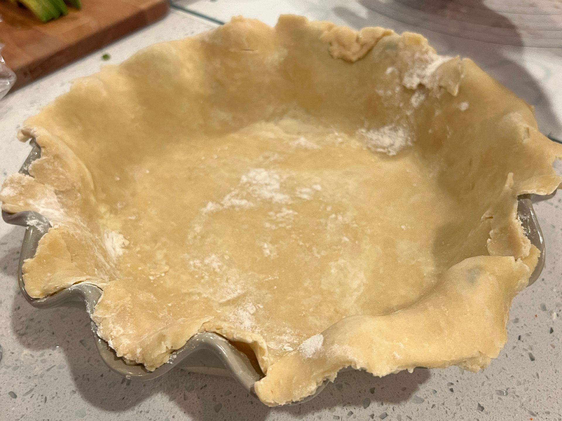 A pie crust is sitting in a pie pan on a counter.