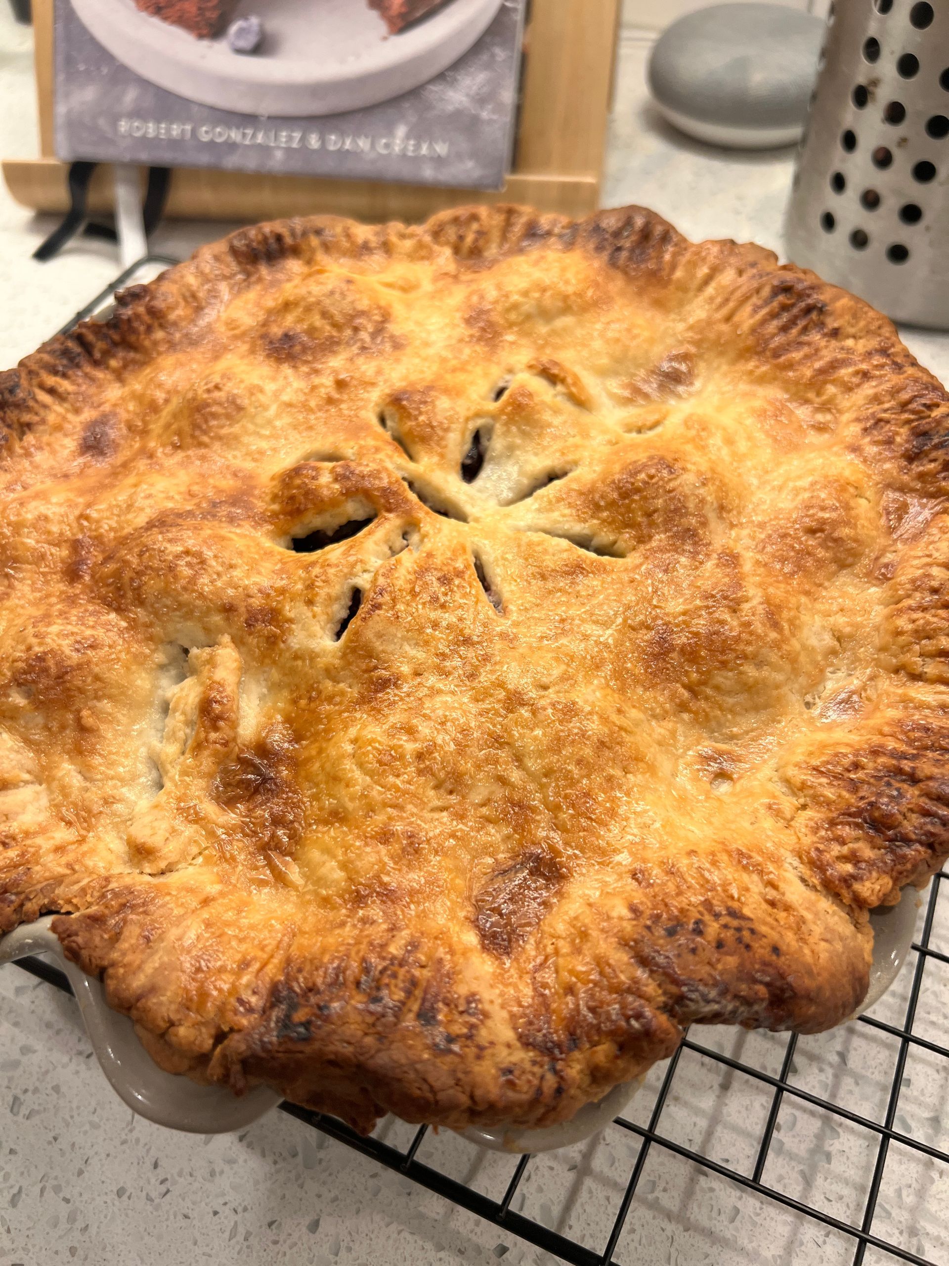 A pie is sitting on a cooling rack on a table.