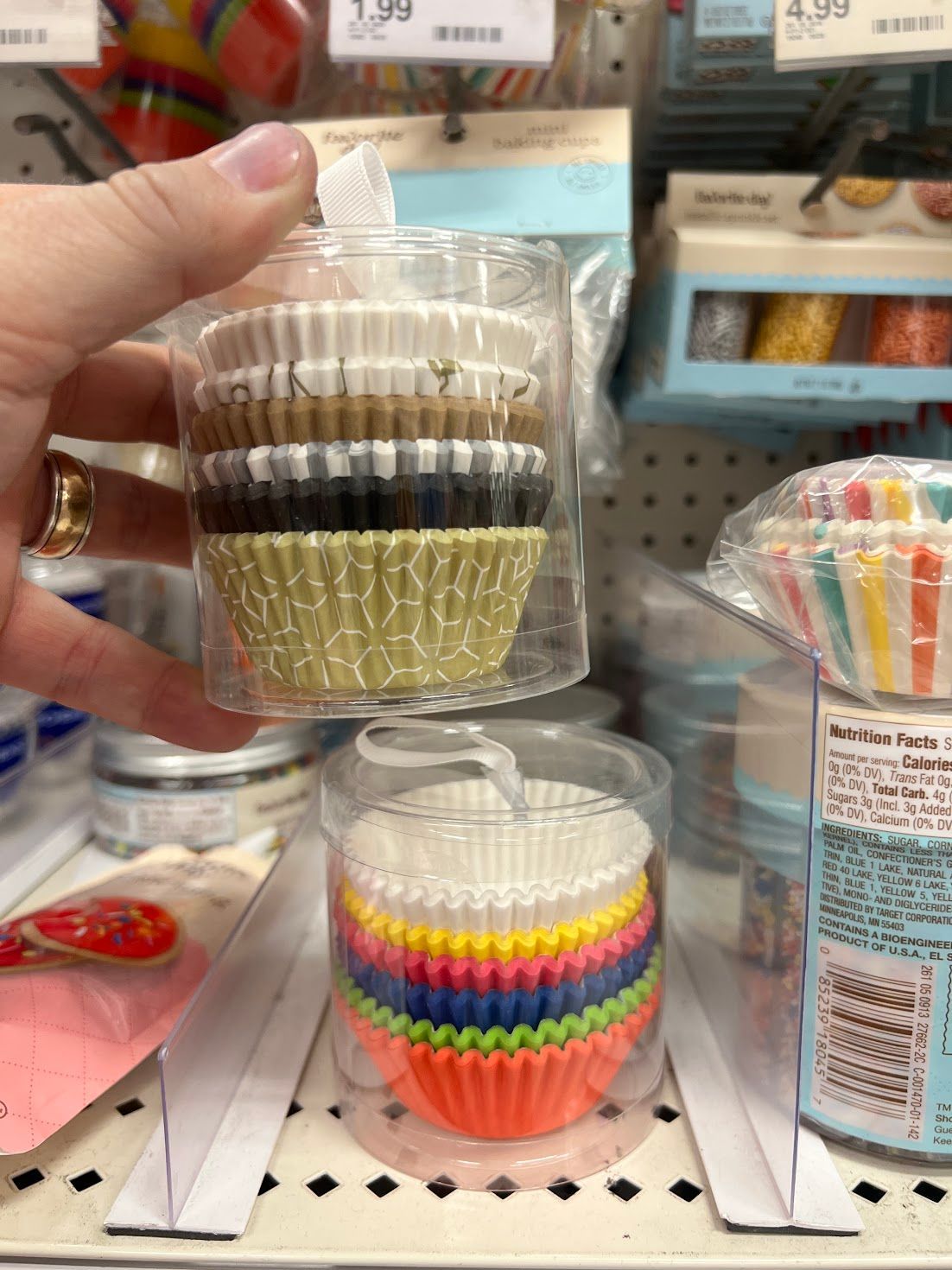A person is holding a package of cupcake liners in their hand.
