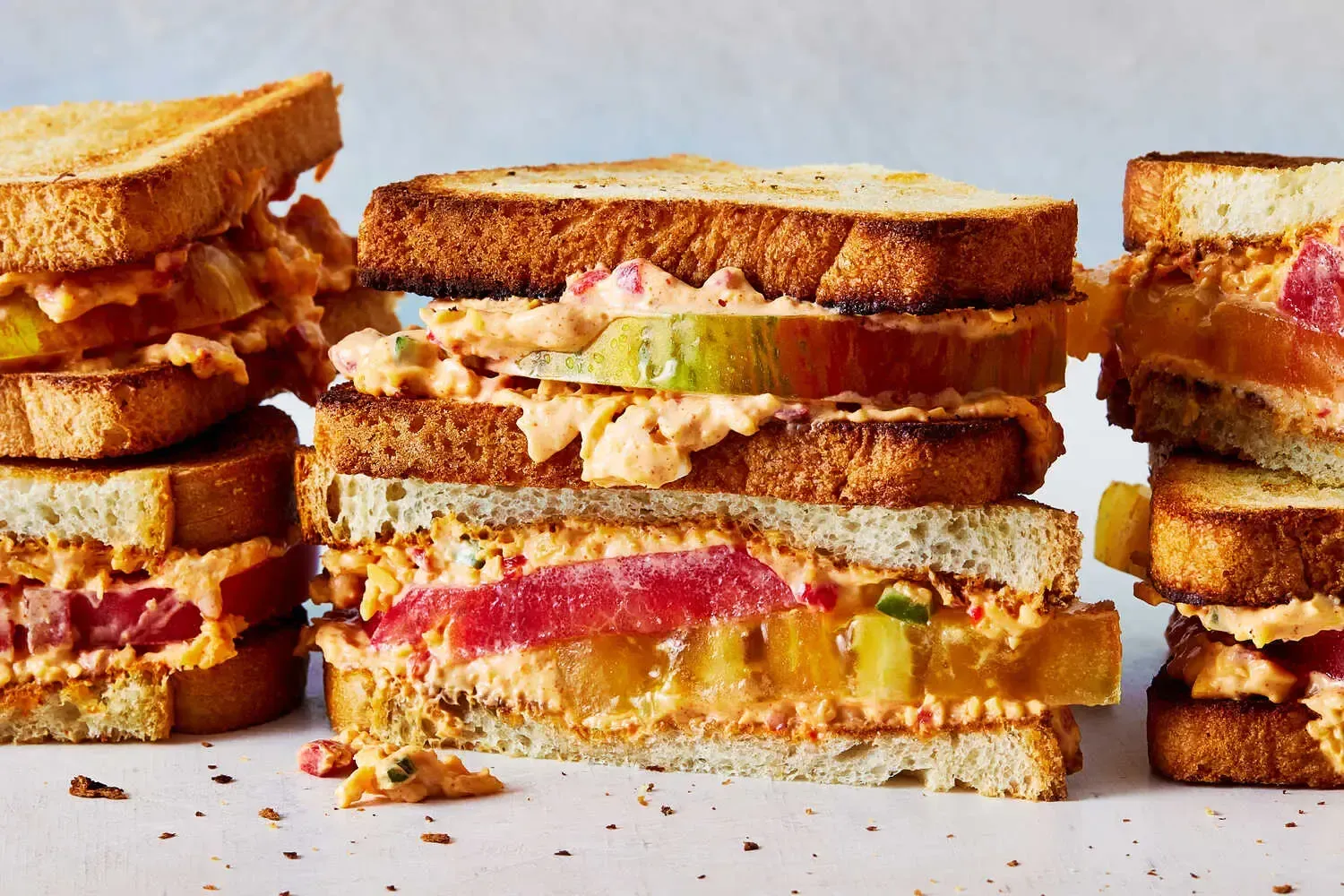 Three sandwiches are stacked on top of each other on a table.