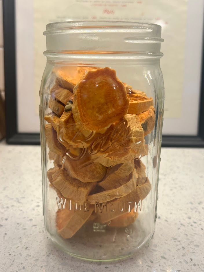 A mason jar filled with sliced sweet potatoes on a counter.