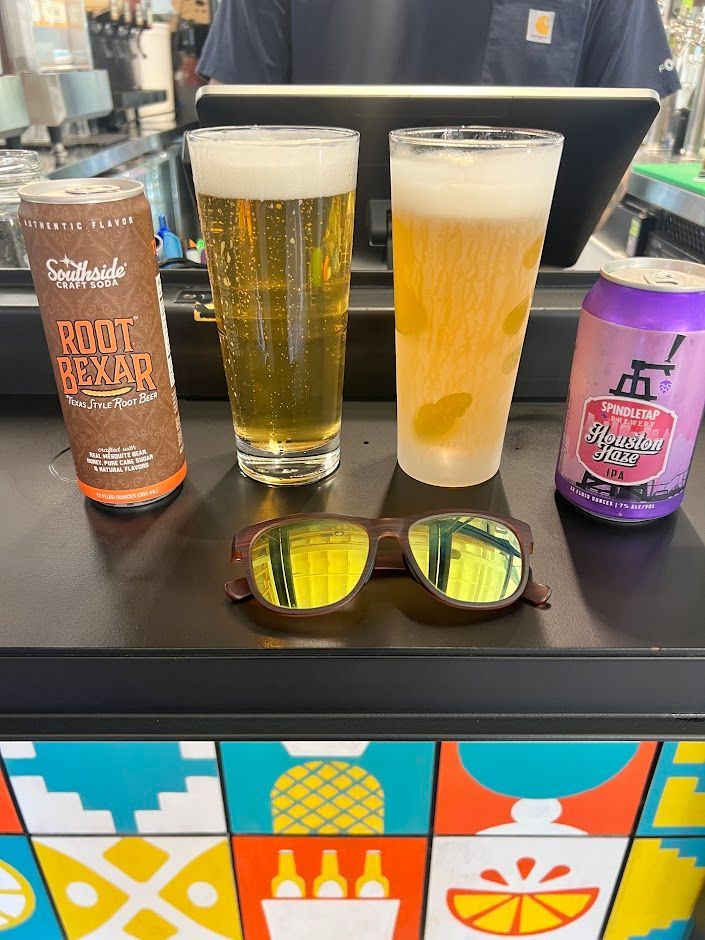 Two glasses of beer and two cans of beer are on a counter.