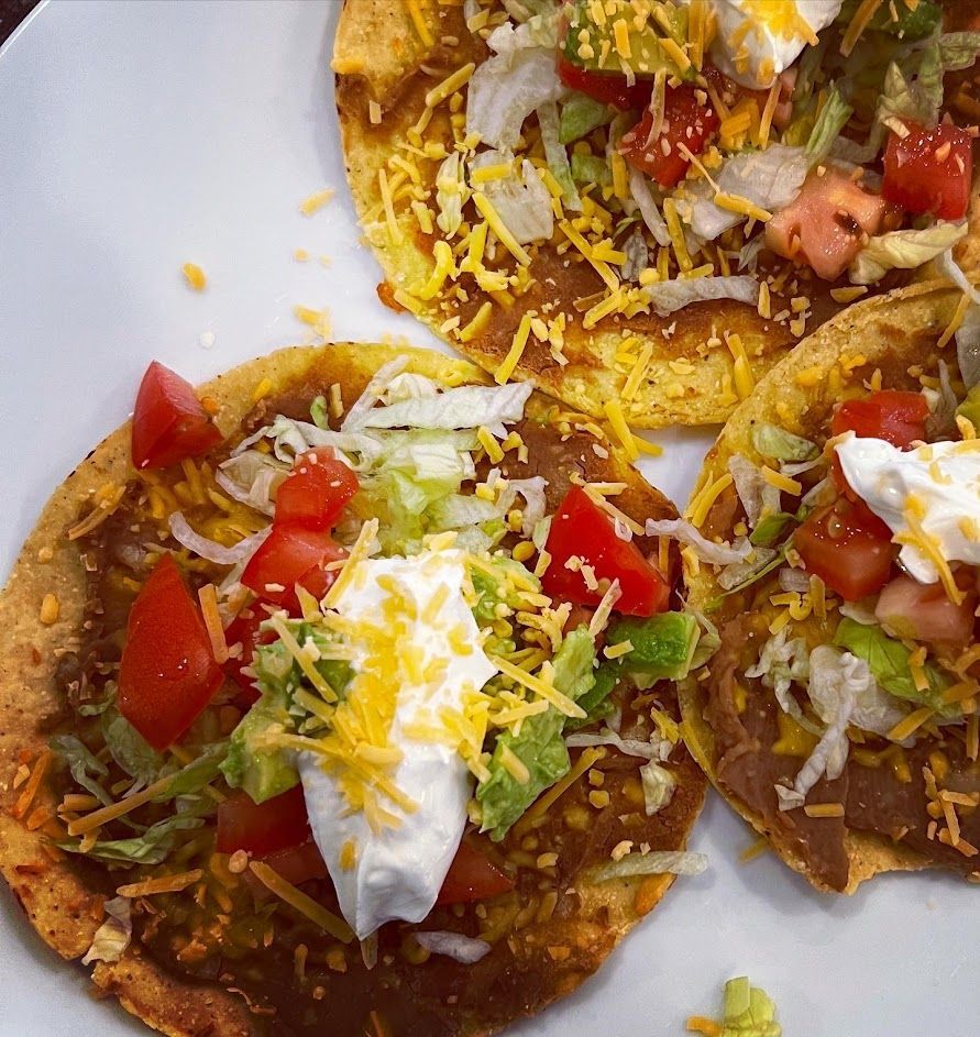 A close up of a plate of tacos with tomatoes and cheese