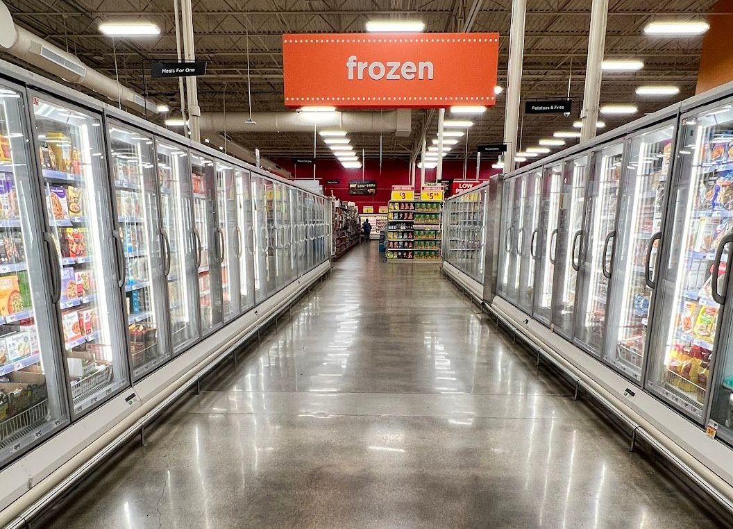 A frozen section of a grocery store with a sign above it.