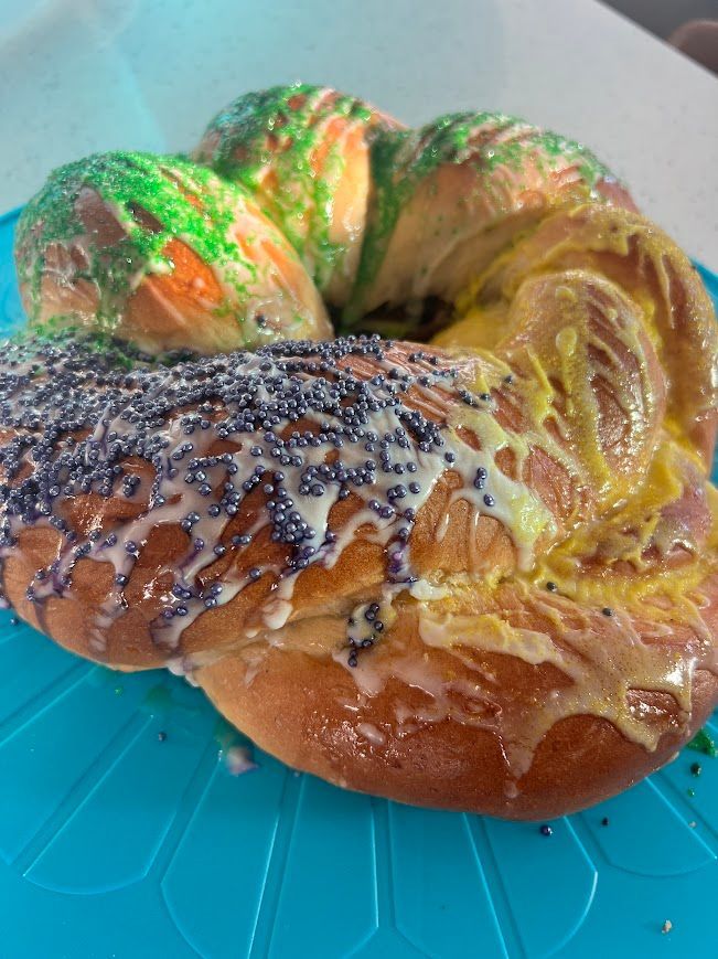 A close up of a king cake on a blue plate.