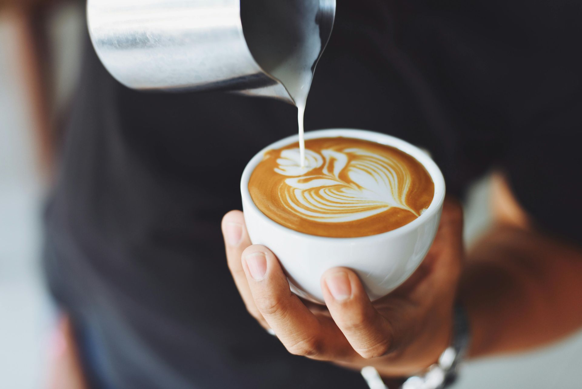 a stock image of a design being poured into a cup of coffee with cream