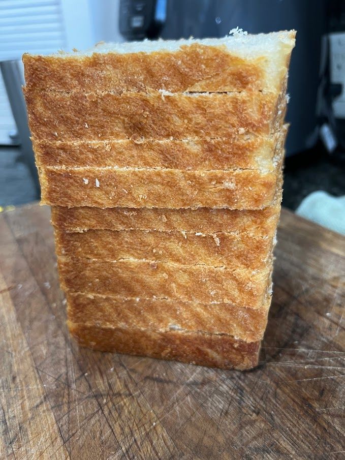 A loaf of bread is sitting on top of a wooden cutting board.