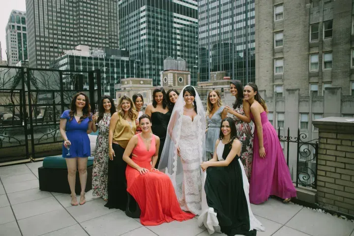 A bride and her bridesmaids are posing for a picture on a rooftop.