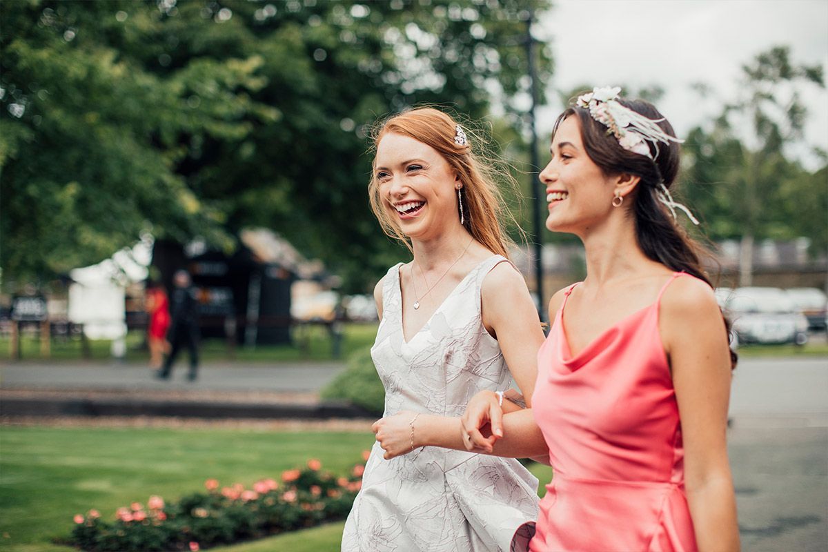 Two women in dresses are walking down a street.