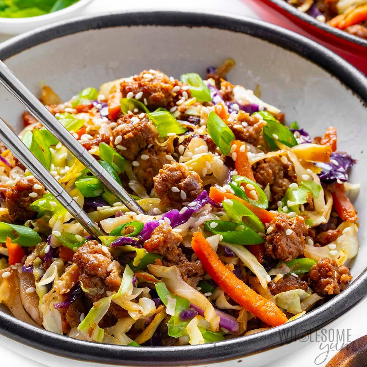 A close up of a bowl of food with chopsticks in it.