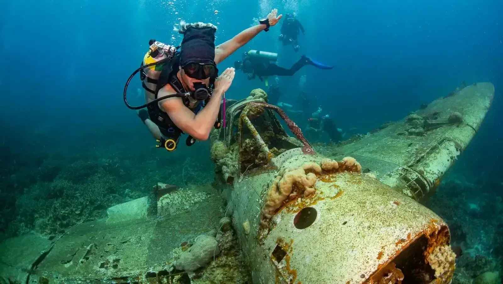 Scuba diver swimming over a sunken airplane wreck underwater