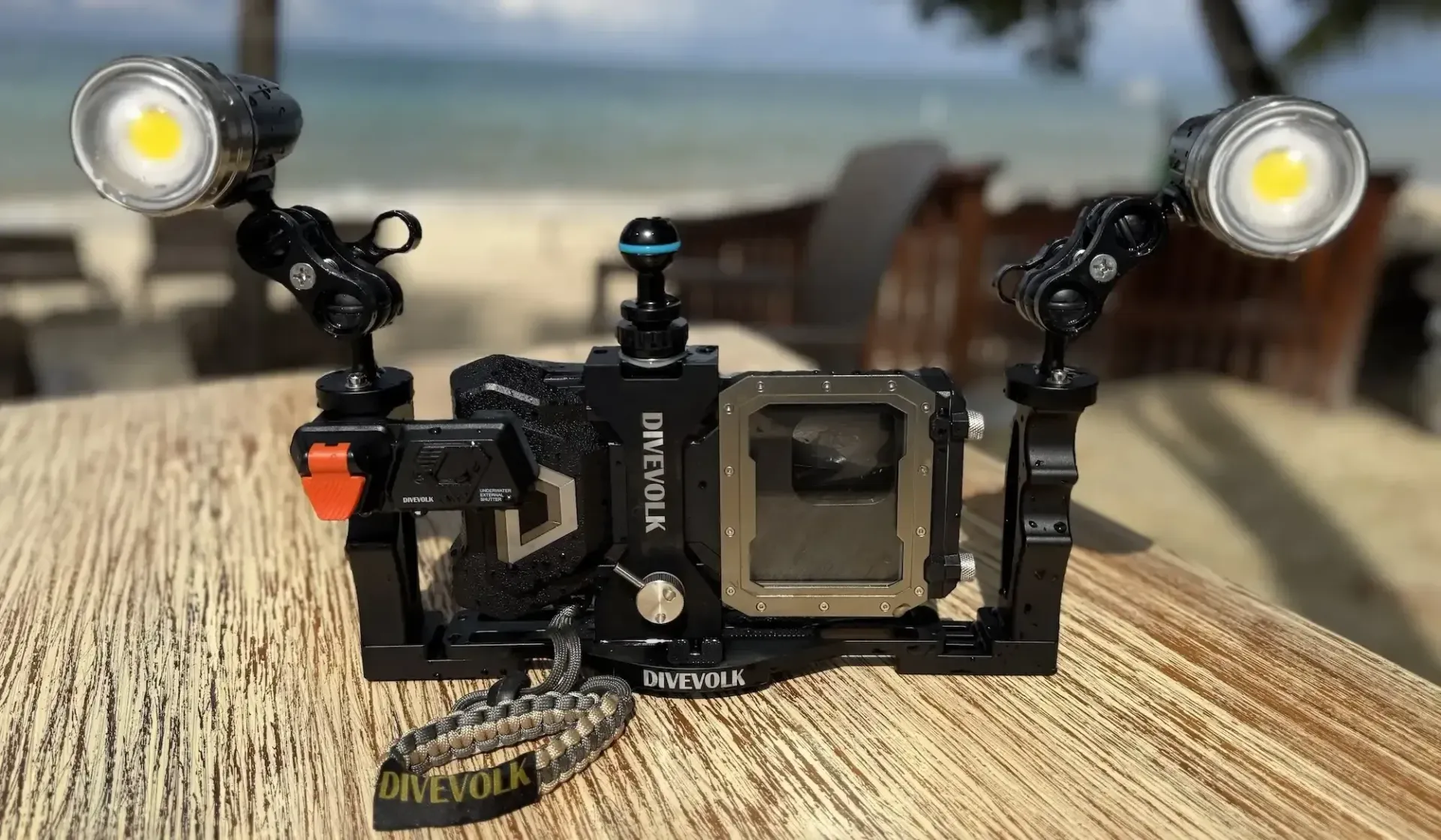 Camera rig with dual LED lights on a wooden table, outdoors with a blurred beach background
