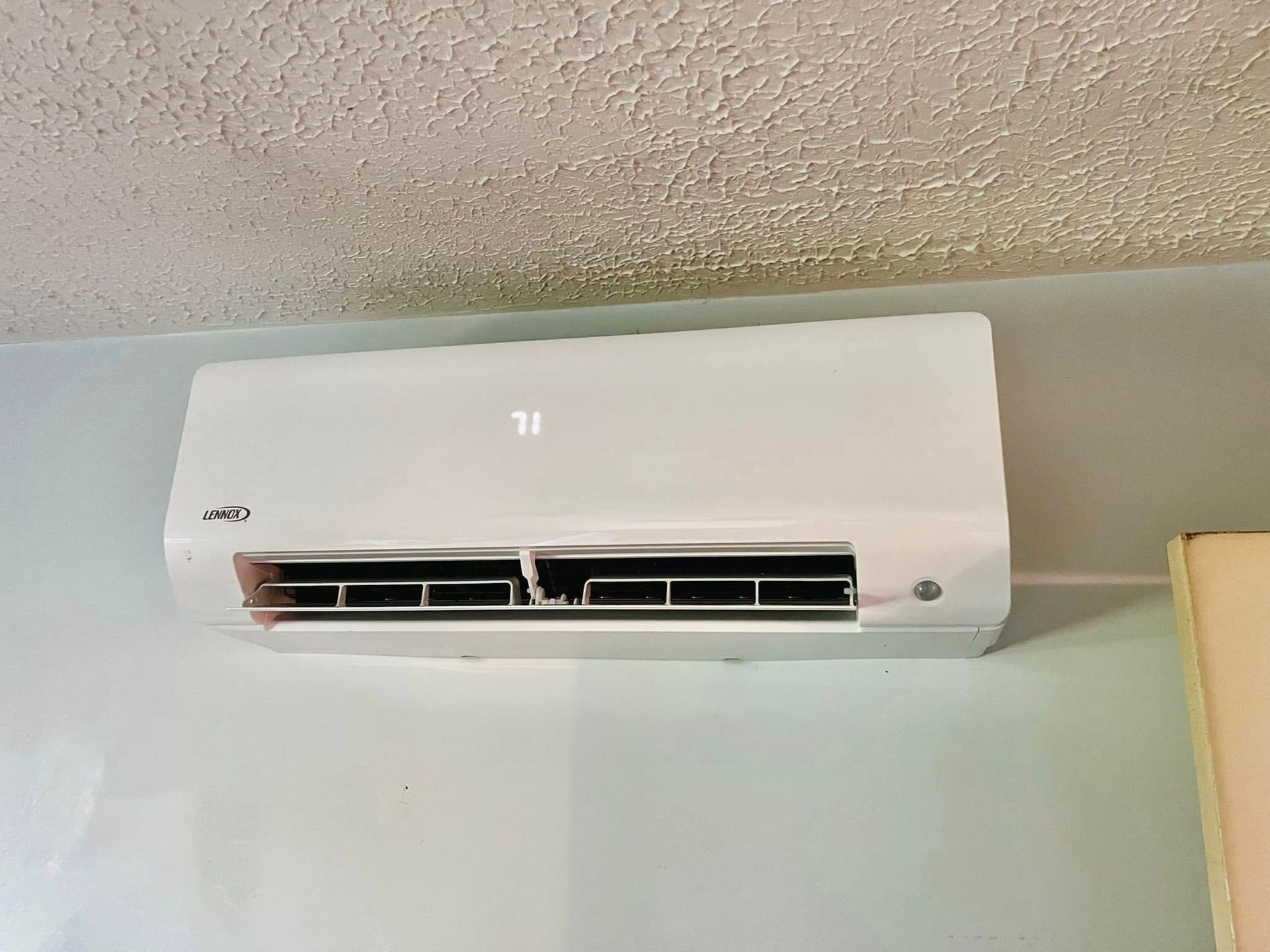 White wall-mounted air conditioner near the ceiling in a room