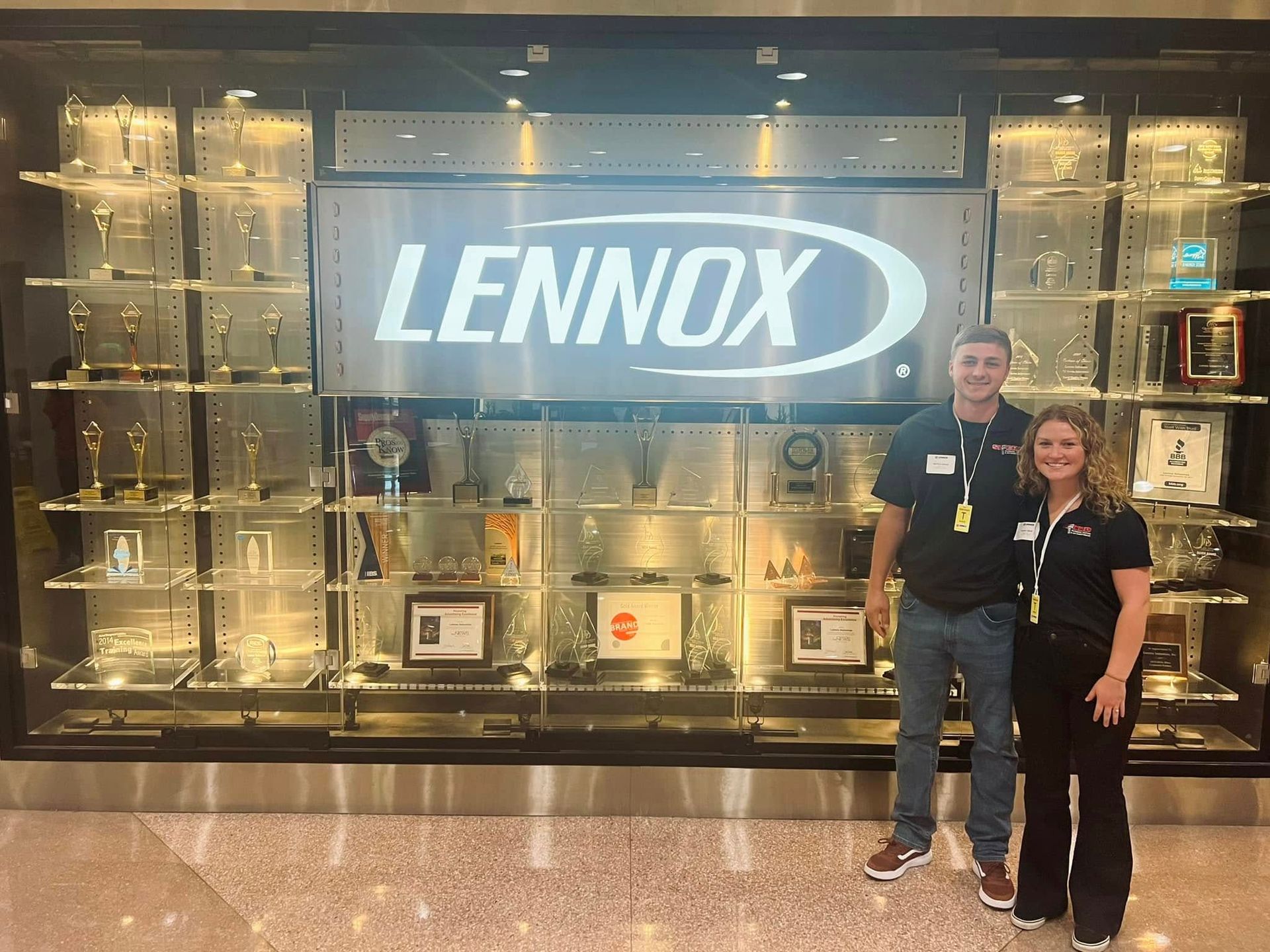 Two people posing in front of a Lennox display case in a showroom