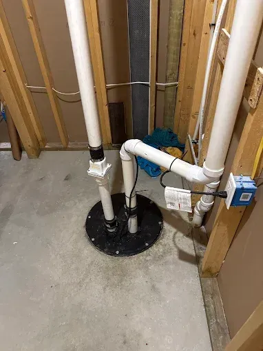 Basement utility area with exposed plumbing pipes and a floor drain in concrete floor