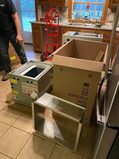 Kitchen floor with a cardboard box, metal box, and overturned chair by the counter
